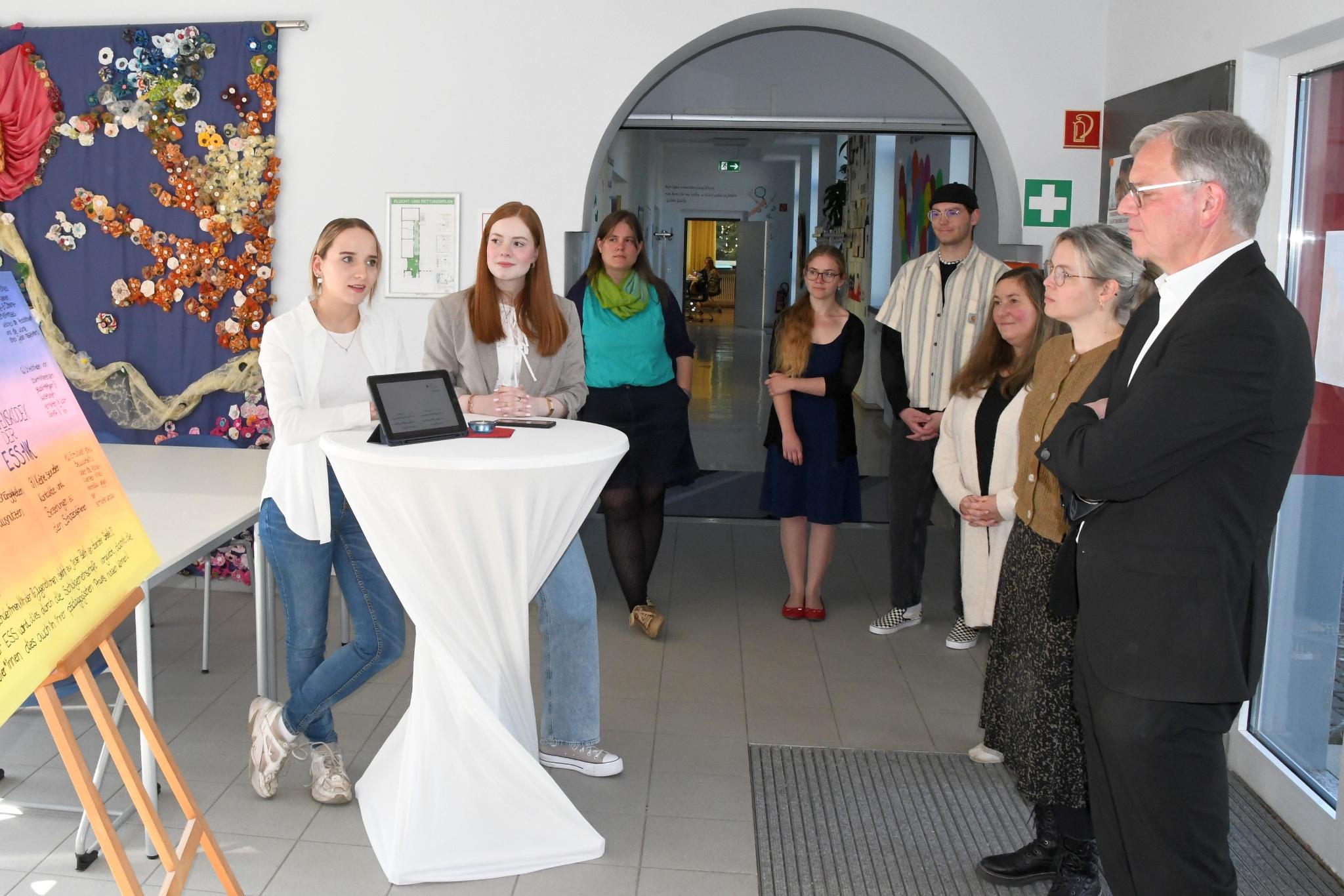 Vivien Schneider und Anna Walle (v. l.) stellen Generalvikar von Plettenberg den Verhaltenskodex der Schule vor.