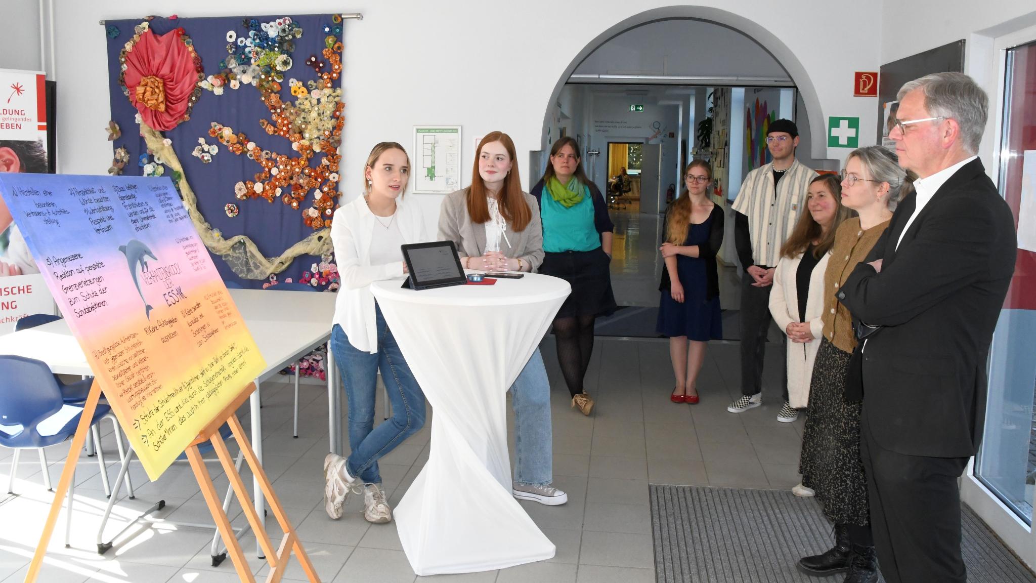 Vivien Schneider und Anna Walle (v. l.) stellen Generalvikar von Plettenberg den Verhaltenskodex der Schule vor.