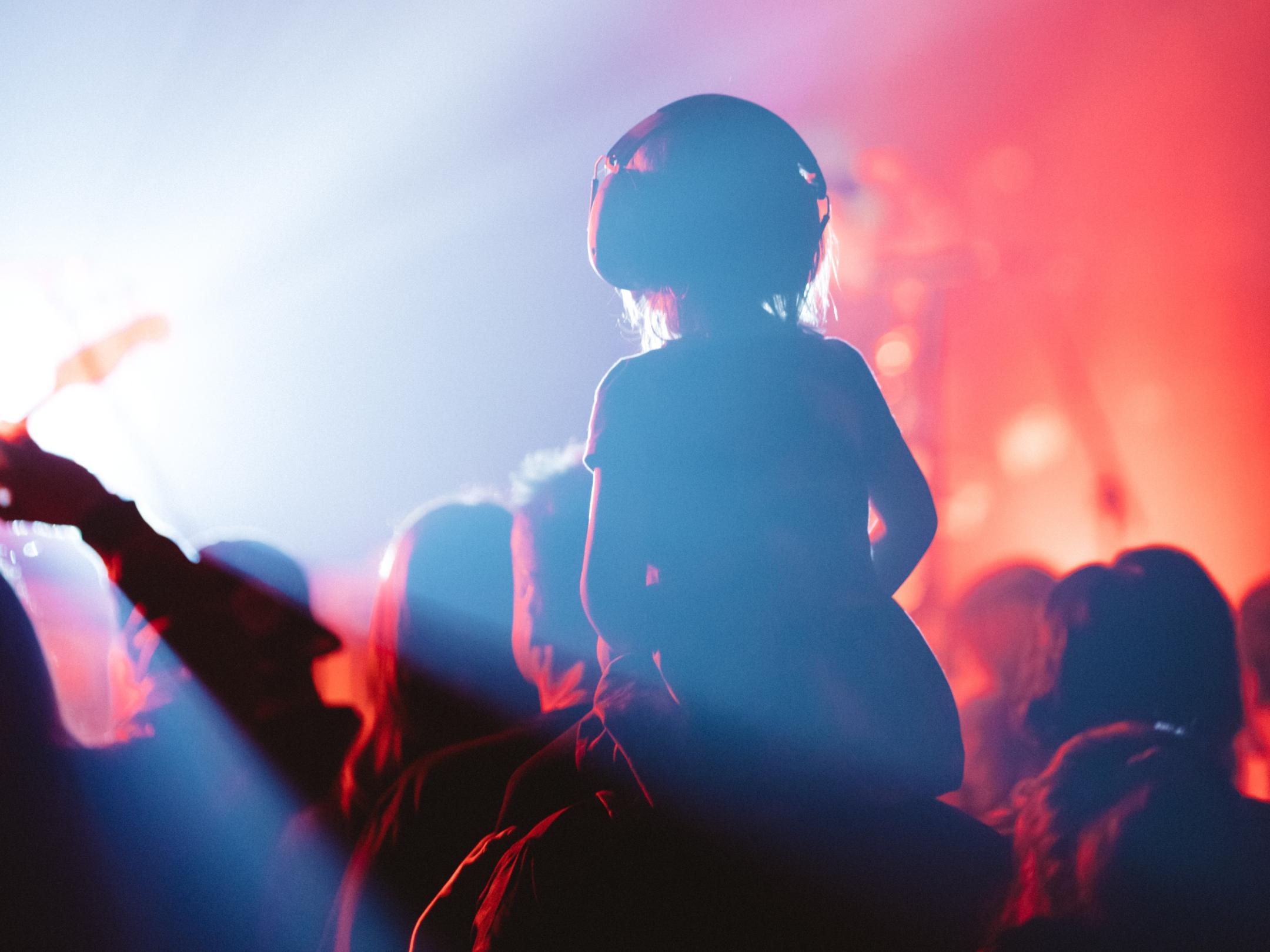 Man sieht einen Menschen mit Kopfhörer auf einem Konzert