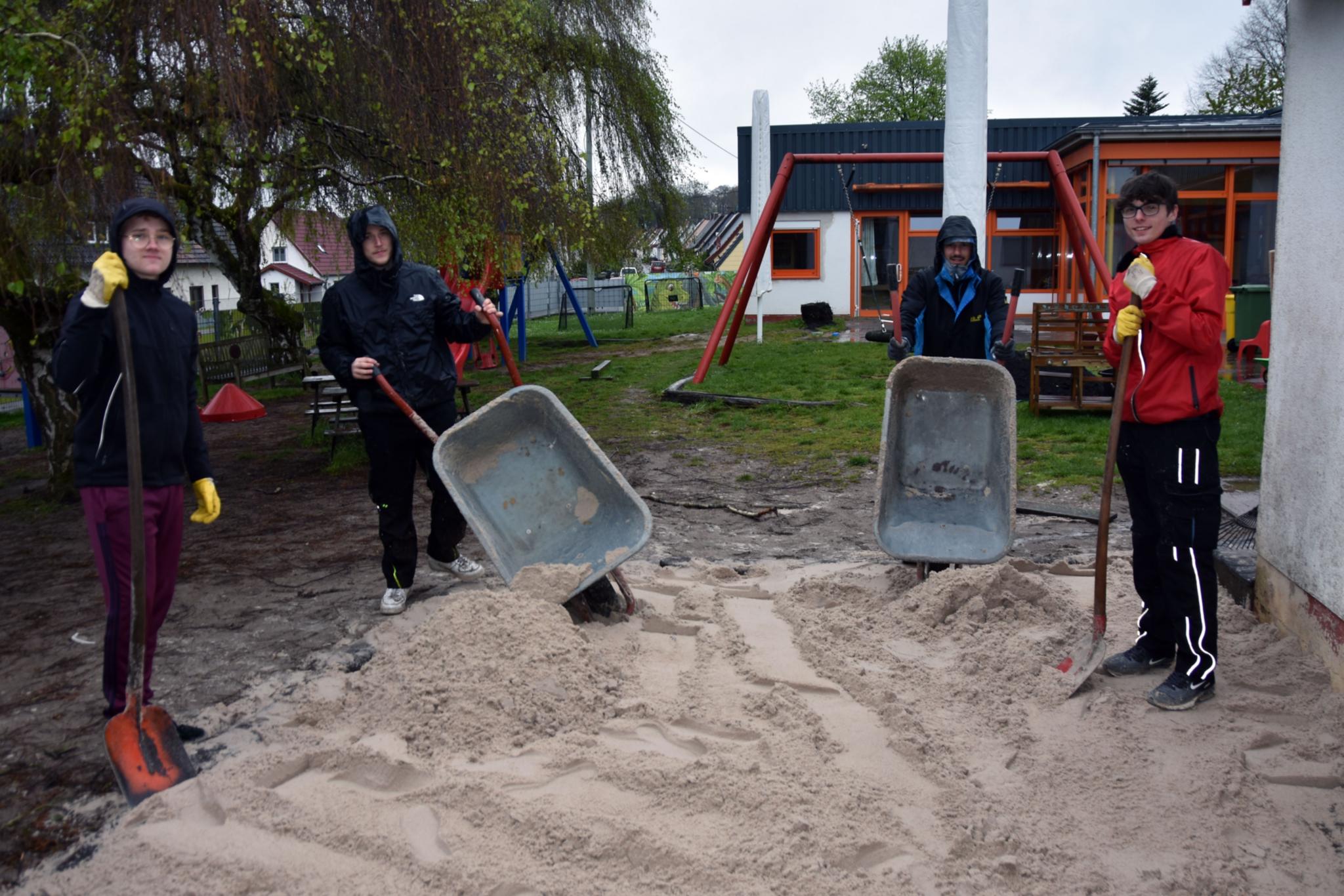 Mit Schubkarren und Schaufeln befüllen Justin, Valentin, Luca und Yannik (vlnr) den Sandkasten der Kita St. Josef mit gespendetem Sand.
